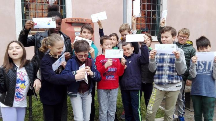 I piccoli studenti della scuola di Borne mostrano le letterine dei loro amici marchigiani