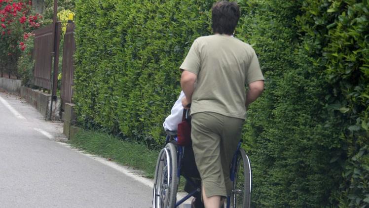 Una badante accompagna un anziano in passeggiata. ARCHIVIO