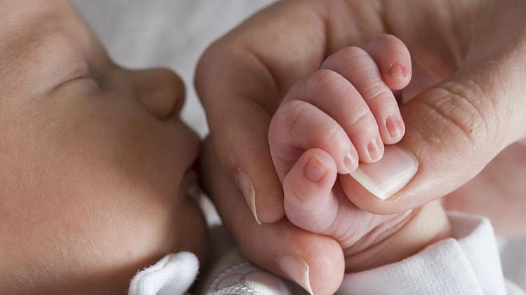 Una tenera immagine di un neonato che stringe la mano della mamma
