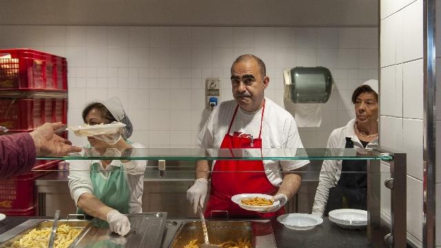 Elio mentre scodella i pasti alla mensa di Milano (FOTO ANSA)
